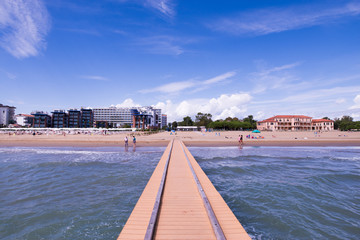 Beach landscape with pier and waves of the sea in the sand
