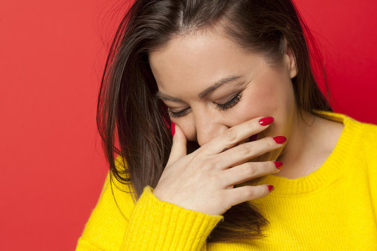 beautiful ashamed woman in a yellow sweater on a red background