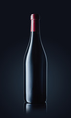 Wine bottle with red wine on dark glossy background. Clipping path included.