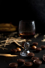 glasses with wine, chocolate and fruit on a dark background