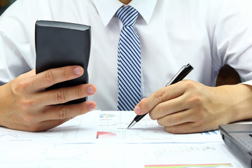 Businessman using calculator with business graph financial.