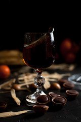 glasses with wine, chocolate and fruit on a dark background