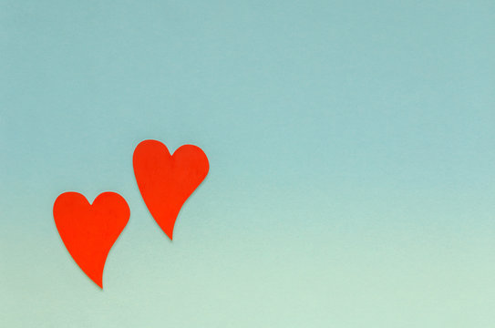 Two wooden red hearts on blue background