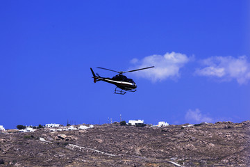 Fototapeta na wymiar A helicopter in the blue sky in Mykonos, Greece