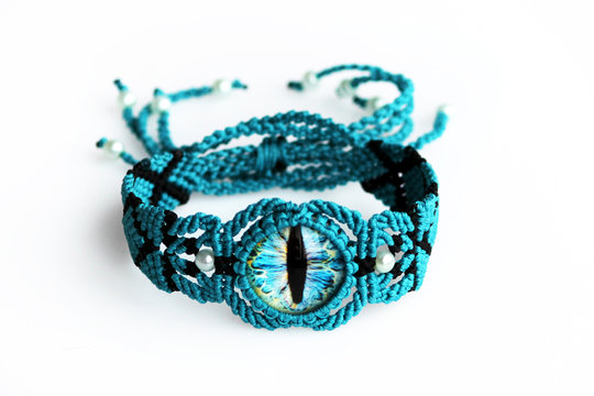 turquoise bracelet for the hand from waxed thread, and dragon eye in the technique of macrame on a white background