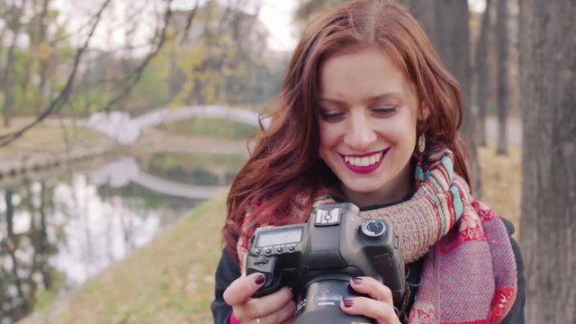 Young attractive woman photographing landscape with digital camera in the autumn park