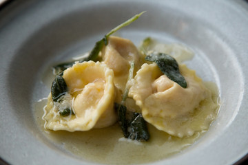 Homemade tortellini/ravioli with buttersauce, parmazan and sage - close up