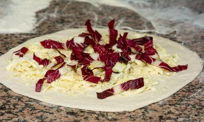 Fresh original Italian raw pizza, dough preparation in traditional style,with cheese and red chicory. Food, italian cuisine and cooking concept.