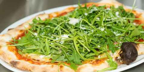 Italian homemade pizza with cheese, onion and fresh arugula. selective focus. Food, italian cuisine and cooking concept. Preparation of the Italian Pizza