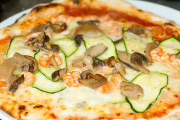 Italian homemade pizza with tomato, zucchini, mushrooms and shrimps. Selective focus. Food, italian cuisine and cooking concept. Preparation of the Italian Pizza