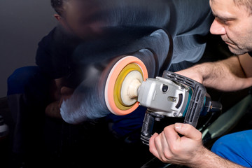 A man polishes a black car with a polisher