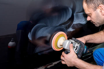 A man polishes a black car with a polisher