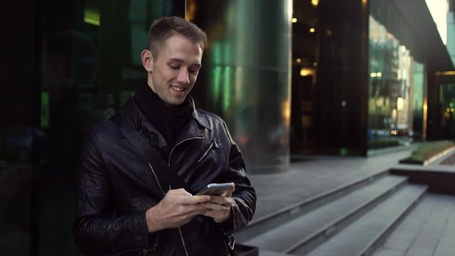 Young handsome man typing text message on smartphone smiling happy on street city 4K