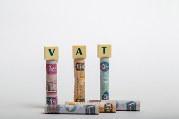 Stacks of  dirham banknotes with the letters VAT  (Value Added Tax) isolated on white background