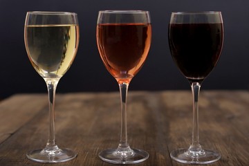 Three different glasses of wine on a wooden surface
