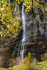 Fototapeta na wymiar Beautiful autumn time at village of Lauterbrunnen in Swiss alps, gateway to famous Jungfrau. Set in a valley featuring rocky cliffs and the roaring, 300m-­high Staubbach Falls