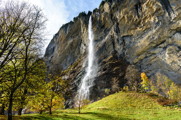 Obraz premium Beautiful autumn time at village of Lauterbrunnen in Swiss alps, gateway to famous Jungfrau. Set in a valley featuring rocky cliffs and the roaring, 300m-­high Staubbach Falls