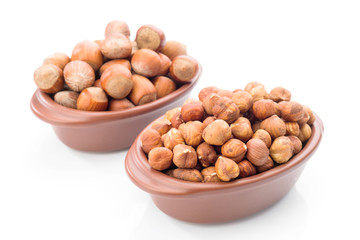 hazelnuts in clay bowl on white background