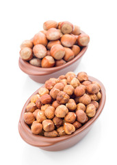 hazelnuts in clay bowl on white background