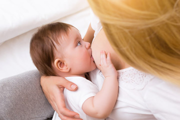 Mother breast feeding and hugging her baby.Young mother feeding breast her babyboy at home in white room. Mom breastfeeding her child whith breast milk