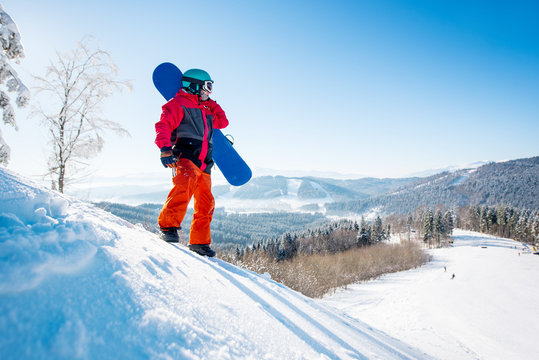 Male snowboarder standing on the snowy slope of the mountain looking away resting after riding in the morning at winter ski resort nature relaxation recreation sports lifestyle active people concept