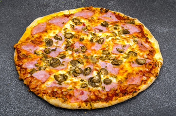 Homemade pizza with ham and mushrooms on gray stone