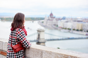 Brunette girl is enjoying beautiful view of the Hungarian Parliament and the chain bridge in Budapest, Hungary. Close-up. Back view. Blurred background