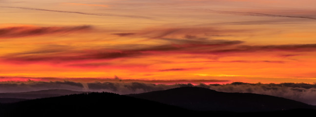 Obraz premium Fire in the sky. A strong play of colors with a strong red glow in the sky over the mountains. Chemtrails created this spectacle. Concept: weather or sunset / sunrise