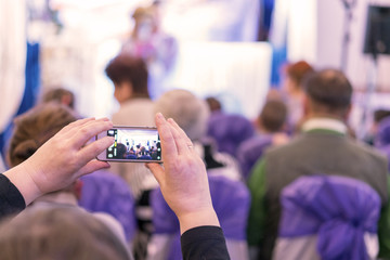 A woman shoots a children's performance on the phone