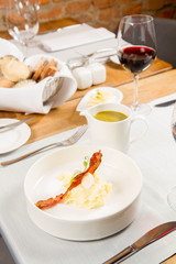 Cream of sorrel and green vegetables soup with quail egg, sour cream, mashed potatoes and crispy bacon served in a jug in a restaurant