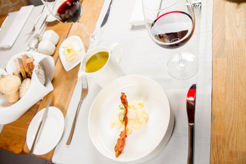 Cream of sorrel and green vegetables soup with quail egg, sour cream, mashed potatoes and crispy bacon served in a jug in a restaurant