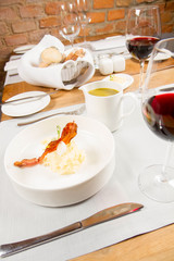 Cream of sorrel and green vegetables soup with quail egg, sour cream, mashed potatoes and crispy bacon served in a jug in a restaurant