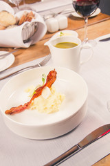 Cream of sorrel and green vegetables soup with quail egg, sour cream, mashed potatoes and crispy bacon served in a jug in a restaurant