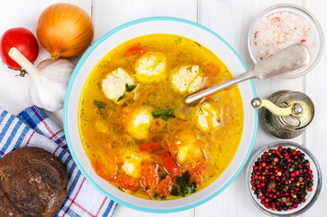 Plate of soup with meatballs on white wooden table