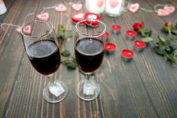 Romantic date concept, red wine glasses and decorations on wooden background