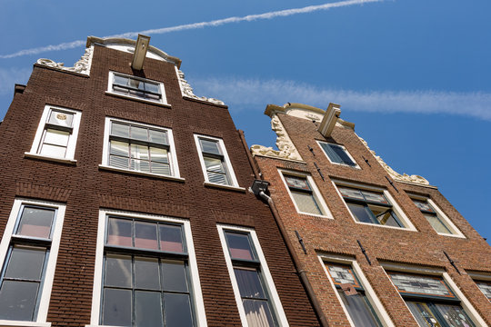 The facade of two historical Dutch houses in Amsterdam.