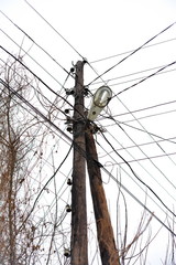 Chaos of cables and wires on electric pole, Messy wires attached to electrics pole in Bangkok, Thailand on blue sky background.
