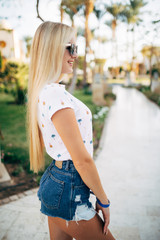 Cheerful young woman in sunglasses in summer palms backgrounds