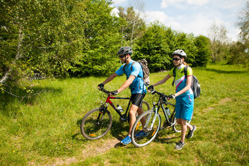 ACTIVE Young couple biking on a forest road in mountain on a spring day