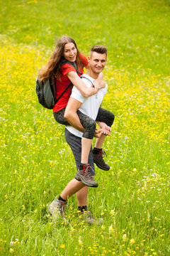 active Playful coupel hiking on a meadow in ratly spring green grass field