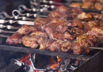 The fried shish kebab cooking on a metal spit. Fried meat is made in a barbecue. On charcoal. Street food.