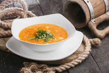 Vegetable soup with bread on wooden tray.