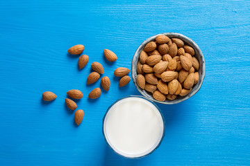 Dairy alternative milk. Almond milk in a glass bottle and fresh nuts over a blue  background, selective focus. Clean eating, dairy-free, vegan, vegetarian, allergy-friendly, healthy food concept