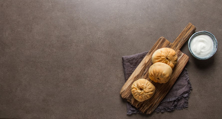 Traditional Russian meat pie, (belyashi) with sour cream. Dark background.