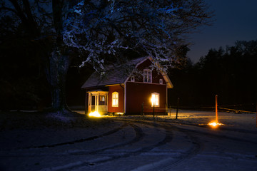 Old red wooden house in wintry Sweden in the evening
