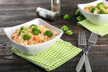 Delicious rice pilaf with broccoli in bowl on wooden table