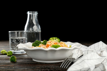 Plate with rice pilaf and broccoli on wooden table