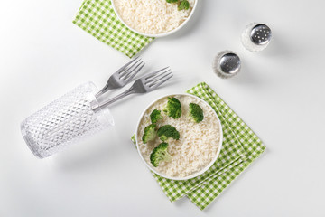 Plate with rice and broccoli on white table