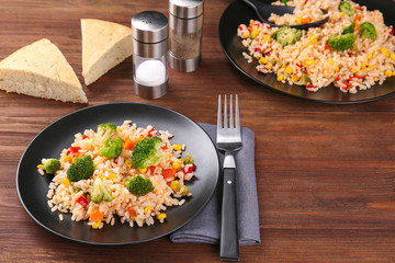 Plate with rice pilaf and broccoli on wooden table