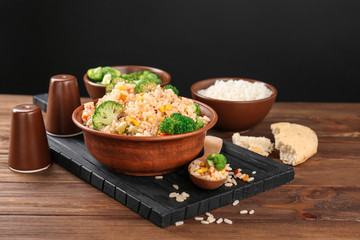 Delicious rice pilaf with broccoli in bowl on wooden table